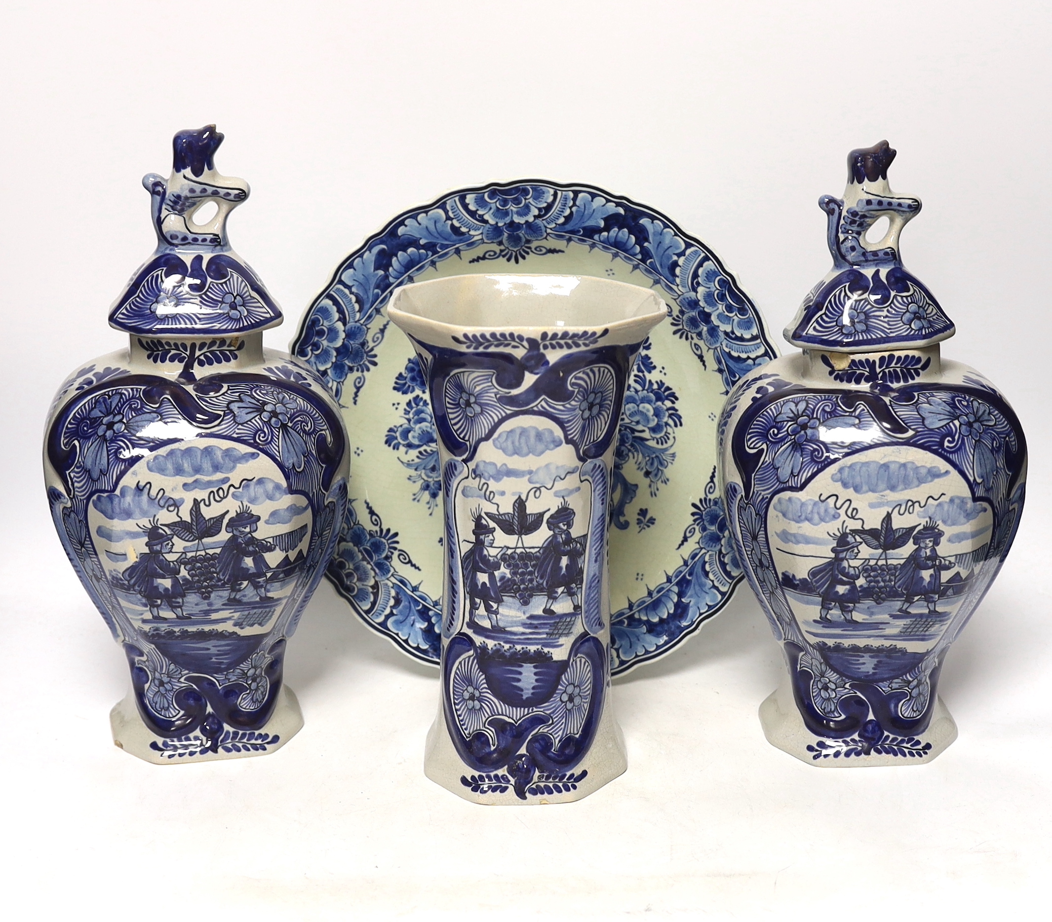 A late 18th century Delft garniture of three vases, two with covers, 32cm, together with a modern Delft plate